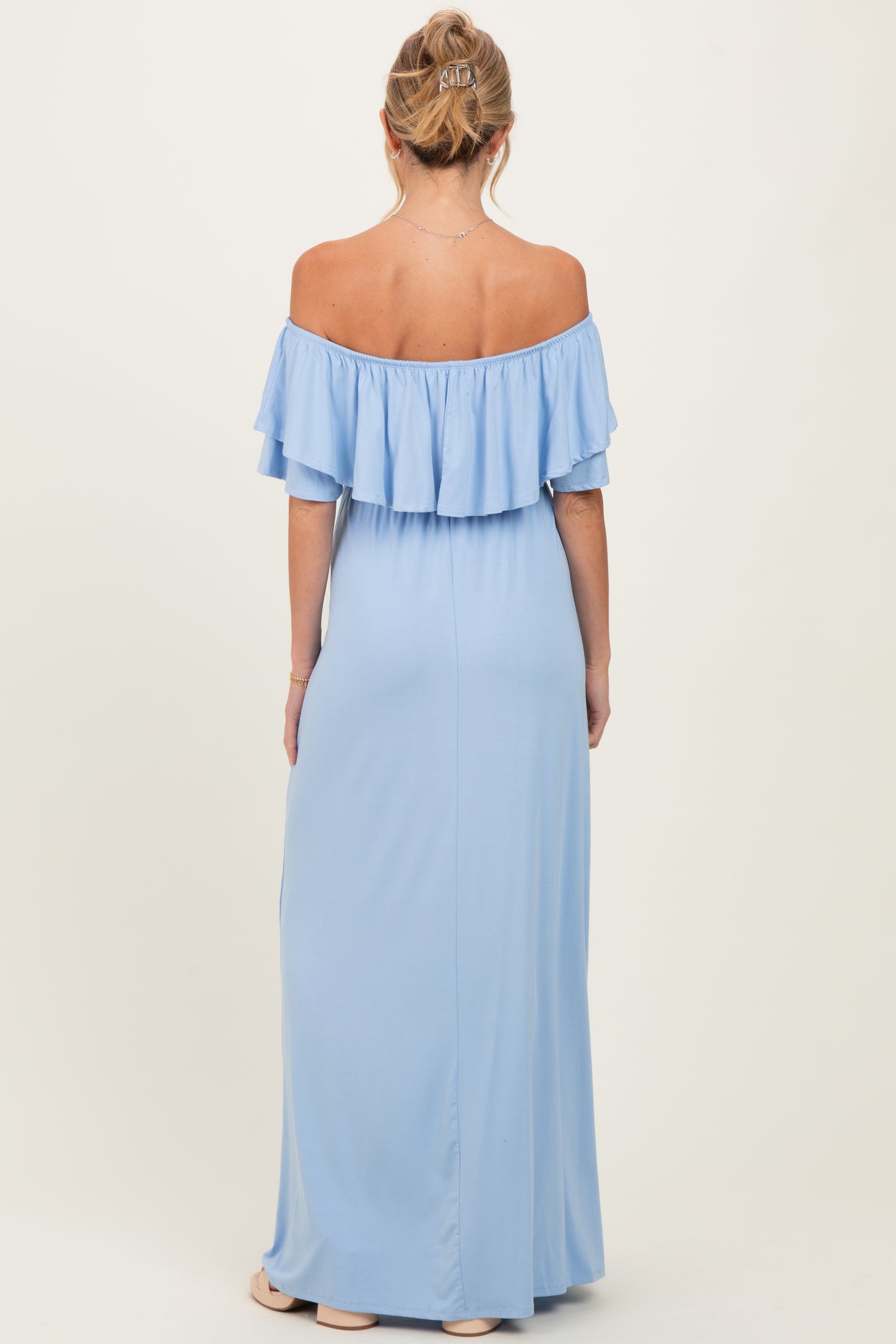 woman wearing a light blue off-the-shoulder maternity maxi dress with a ruffled neckline