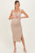woman wearing a beige ribbed maternity dress with a side slit, gently cradling her baby bump