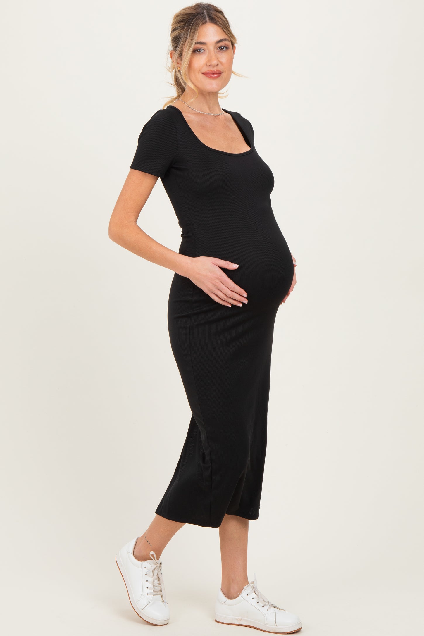 woman wearing a black short sleeve maternity dress and showing her baby bump
