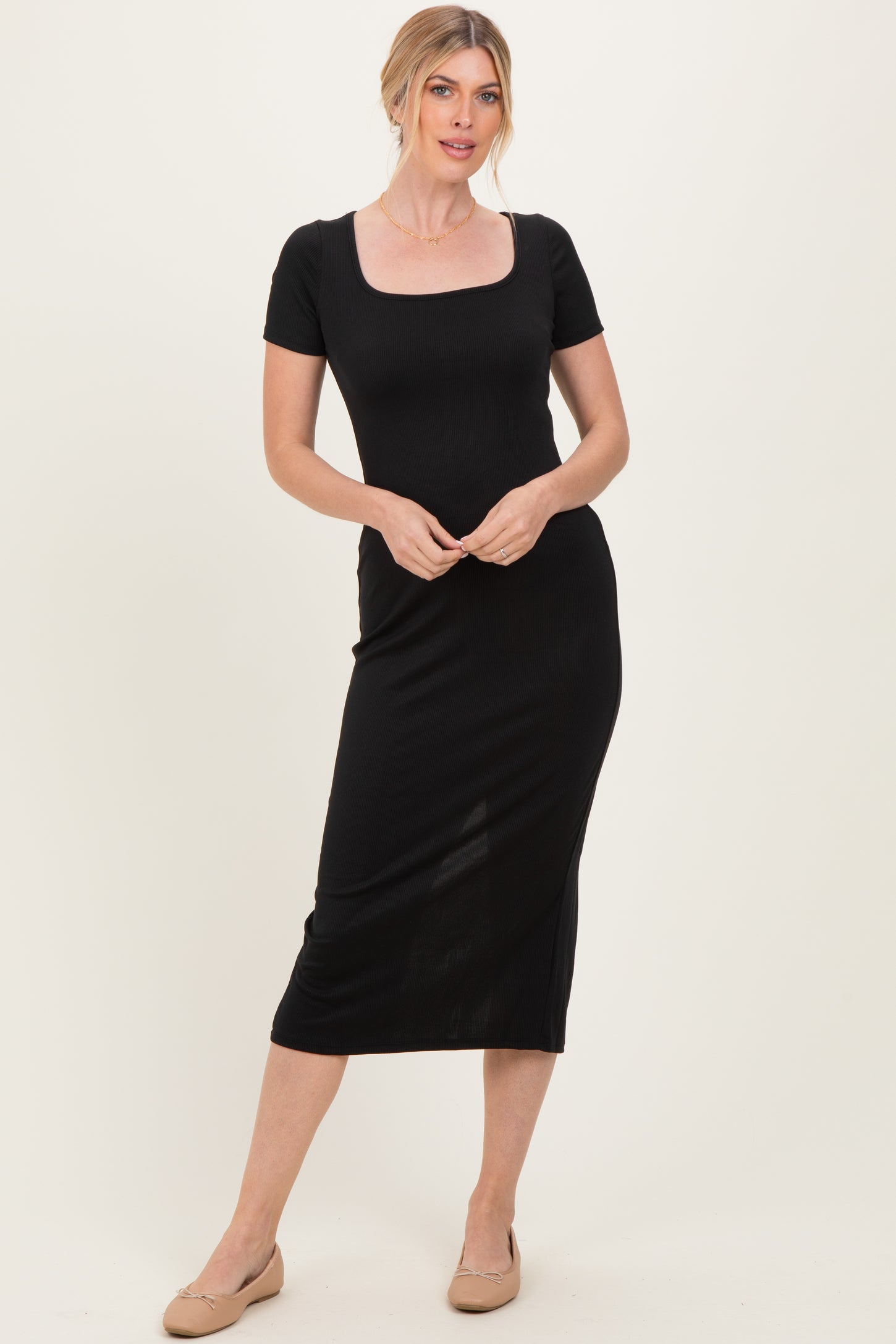 woman wearing a black short sleeve midi dress with a square neckline and fitted silhouette