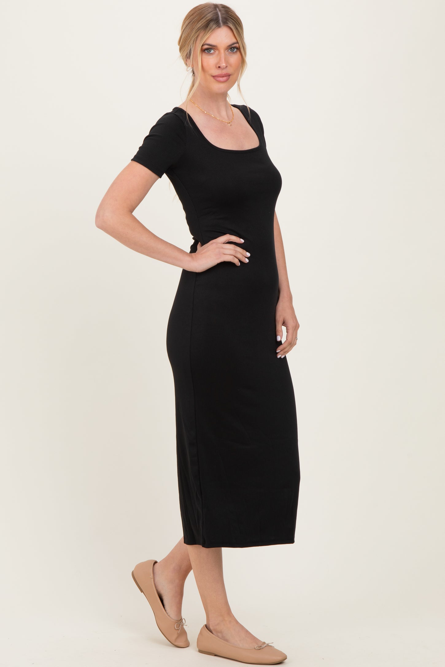 woman wearing a black ribbed midi dress with a square neckline and short sleeves, styled with ballet flats