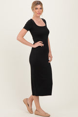 woman wearing a black ribbed midi dress with a square neckline and short sleeves, styled with ballet flats