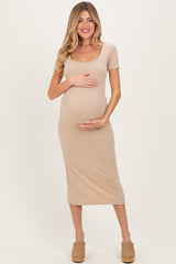 woman wearing a beige short sleeve maternity dress and holding her baby bump