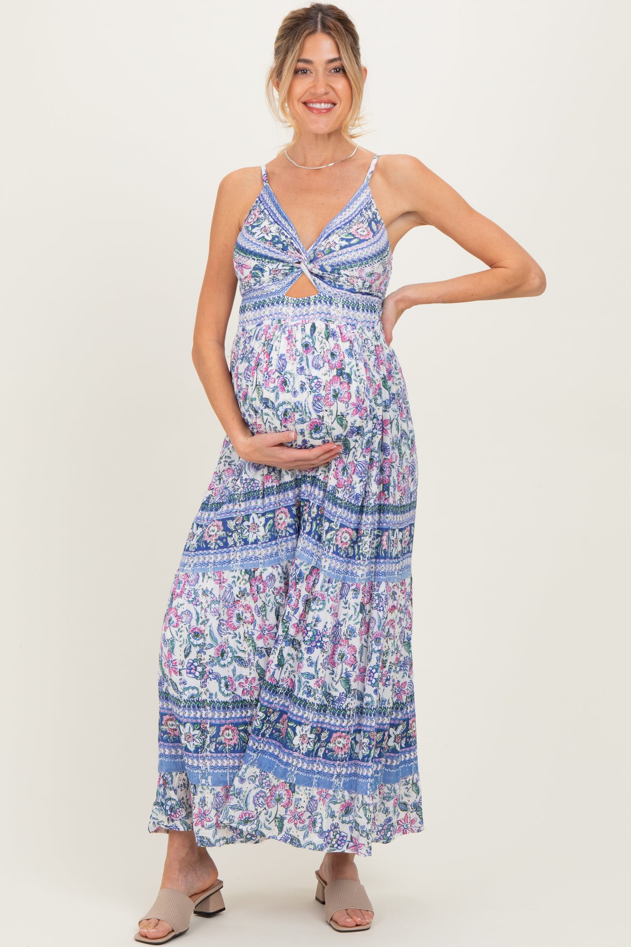 woman wearing a patterned maxi maternity dress with spaghettis straps and holding her baby bump