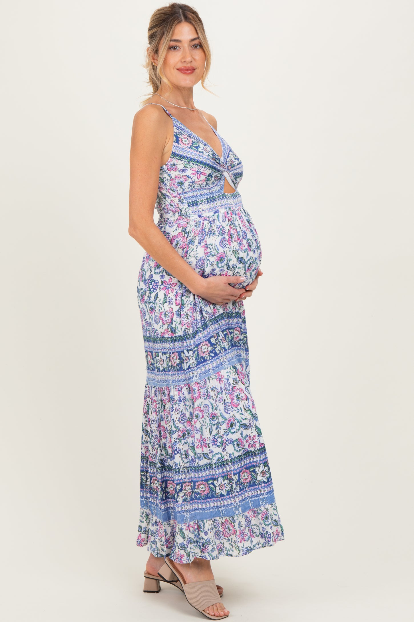 woman wearing a blue floral print maternity maxi dress and showcasing her baby bump