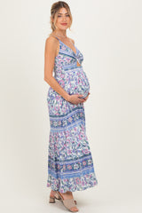 woman wearing a blue floral print maternity maxi dress and showcasing her baby bump