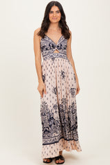 woman wearing a light pink floral maxi dress with navy blue patterns and a crisscross bodice