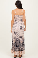 woman wearing a sleeveless pink maxi dress with navy floral print and smocked back detailing