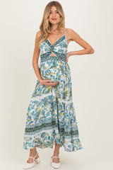 woman wearing a floral print maternity maxi dress, showing off her baby bump with a stylish crisscross design