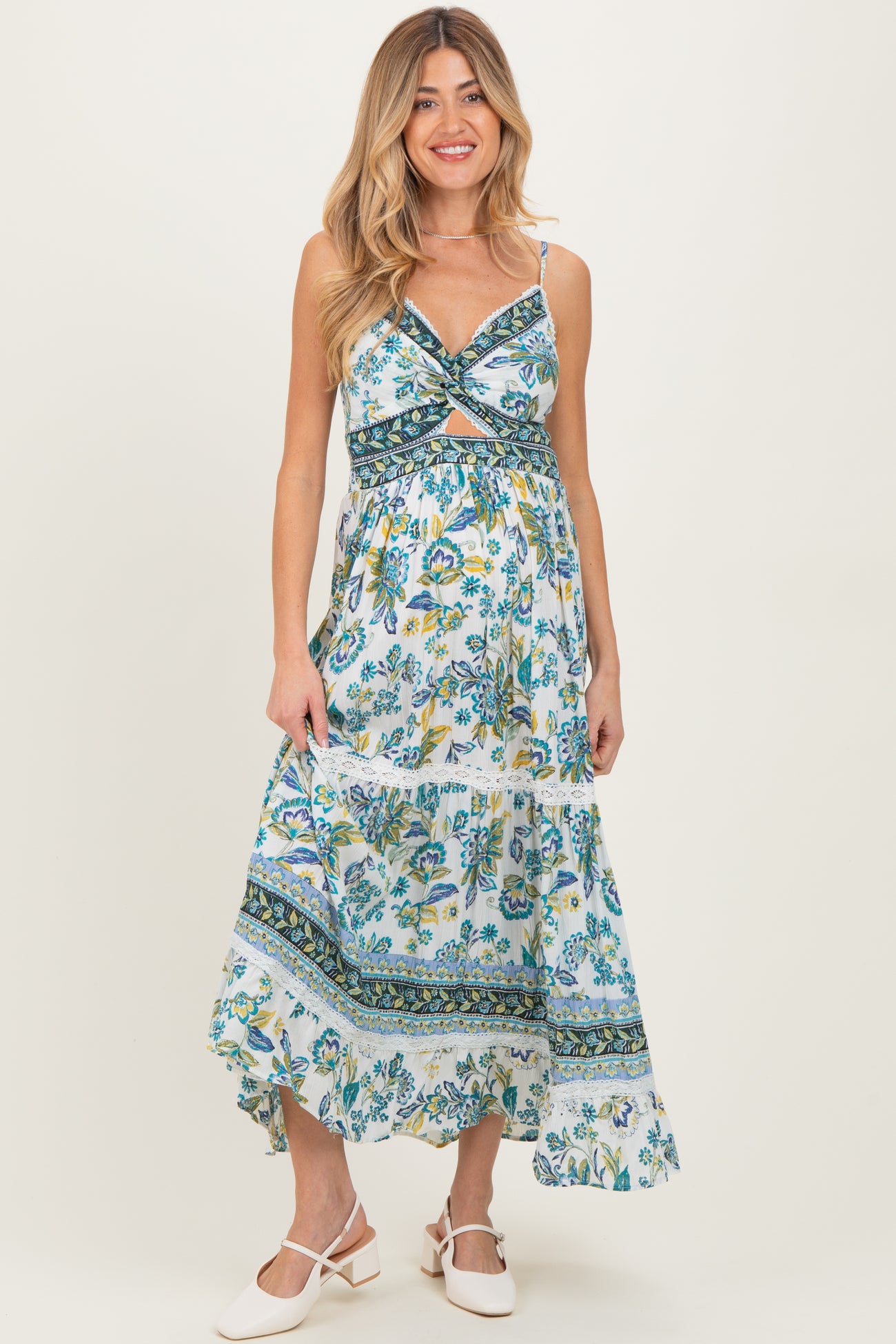 woman wearing a blue floral maternity maxi dress with a twist front and tiered skirt, showing her baby bump