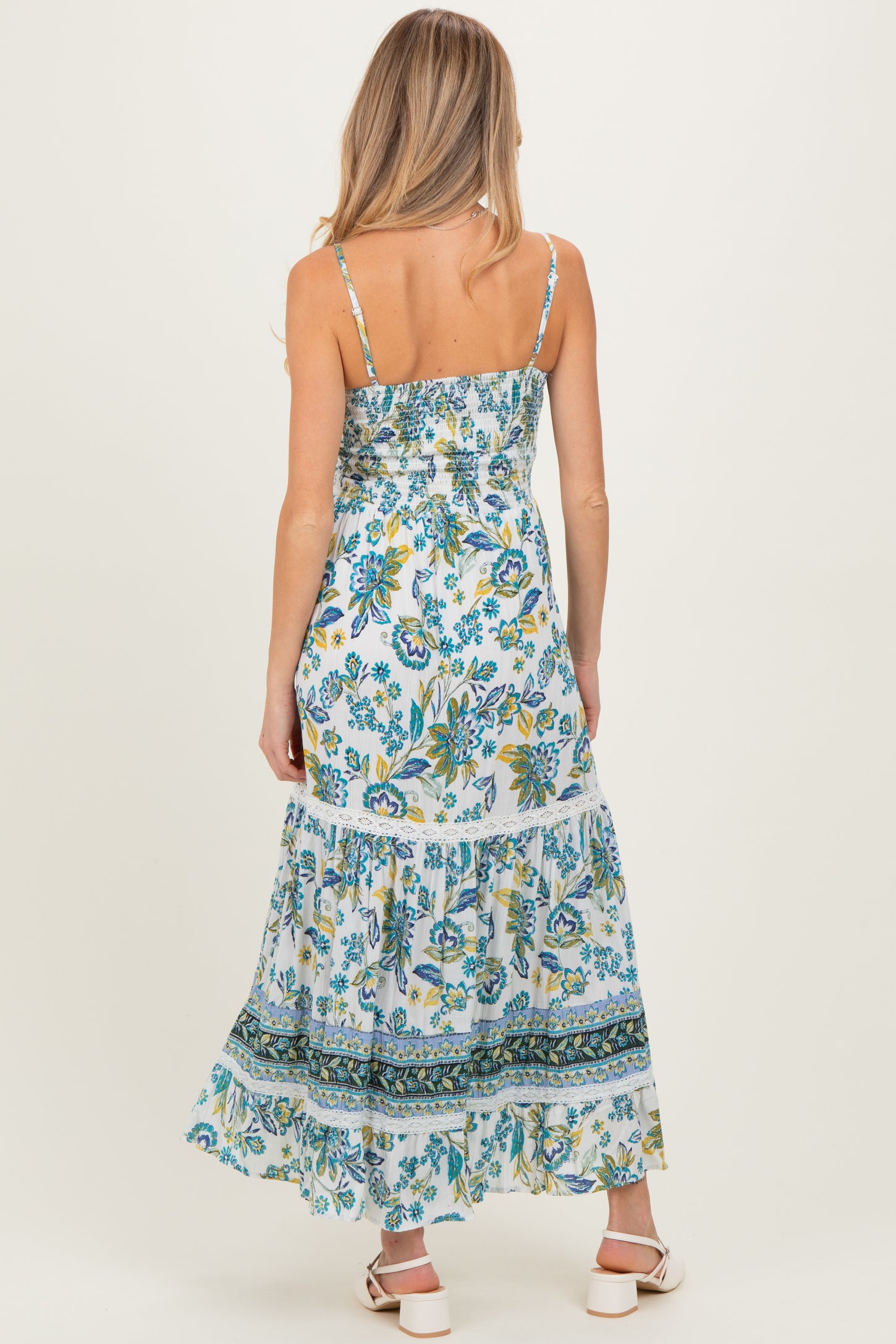 woman wearing a floral maxi maternity dress with a tiered skirt and adjustable spaghetti straps