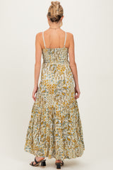 woman wearing a floral maxi maternity dress with a smocked back and tiered skirt, showing her baby bump