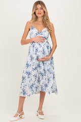 woman wearing a floral maternity wear midi dress in white and blue, holding her baby bump