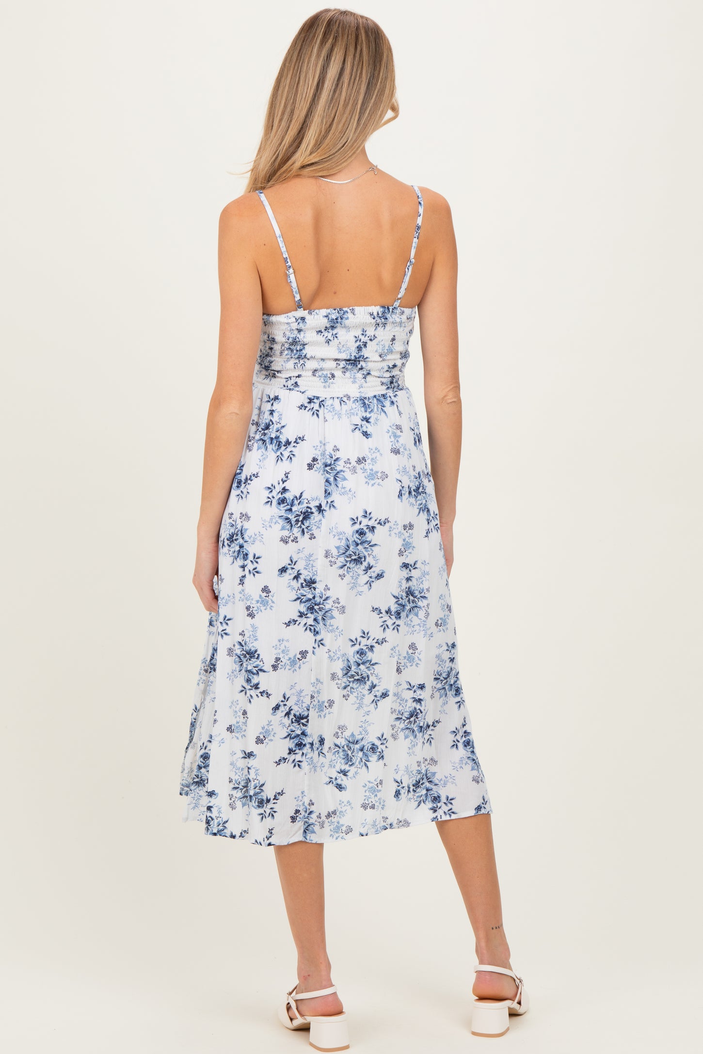 woman wearing a blue and white floral maternity dress with adjustable straps and a flowy skirt