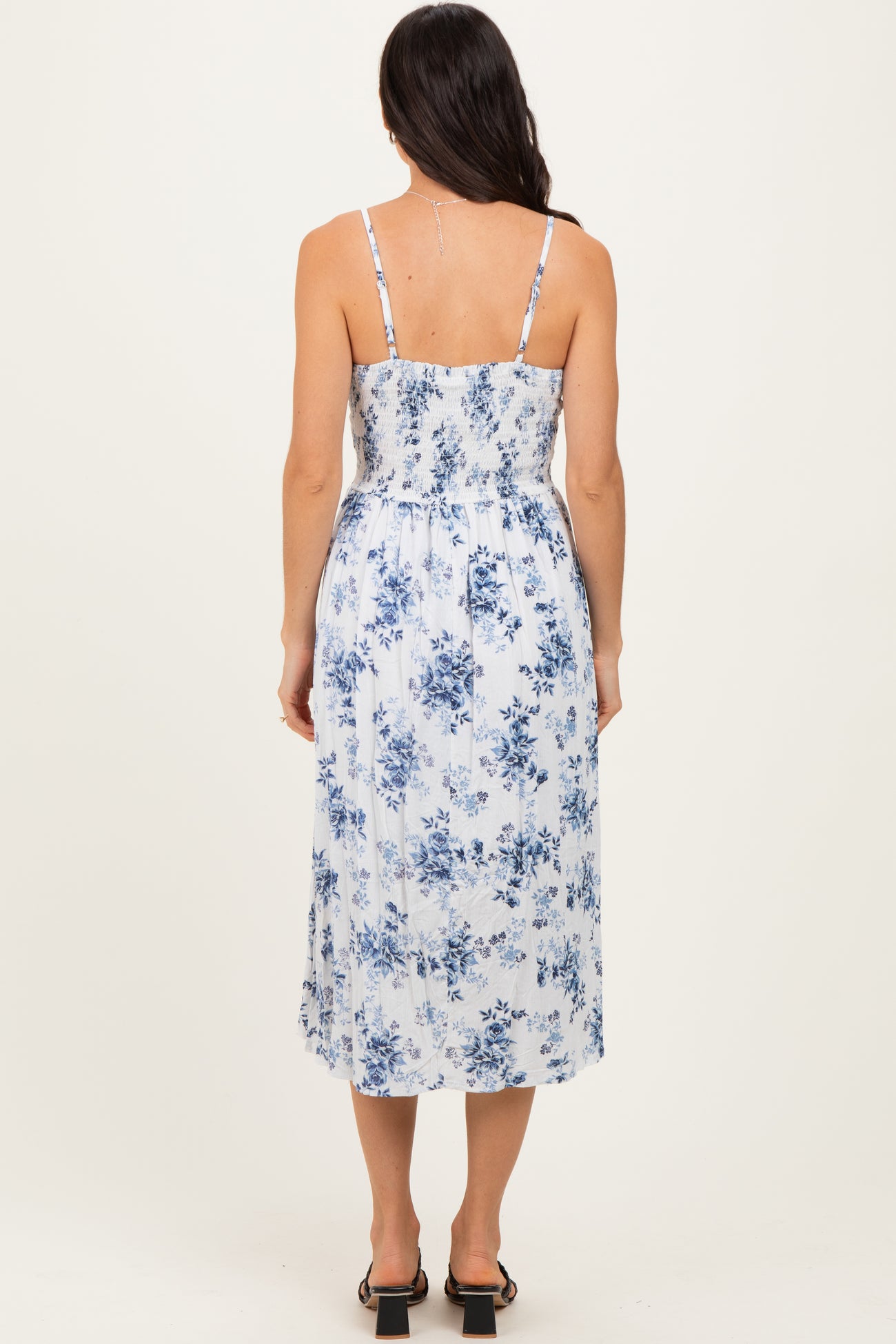 woman wearing a blue and white floral midi dress with adjustable spaghetti straps and a smocked back