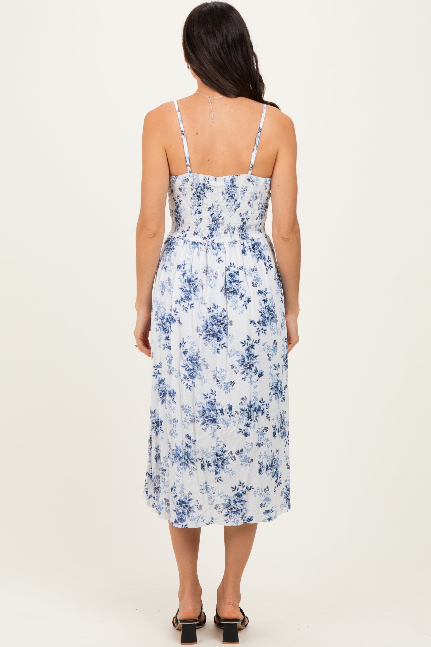 woman wearing a blue and white floral midi dress with adjustable spaghetti straps and a smocked back
