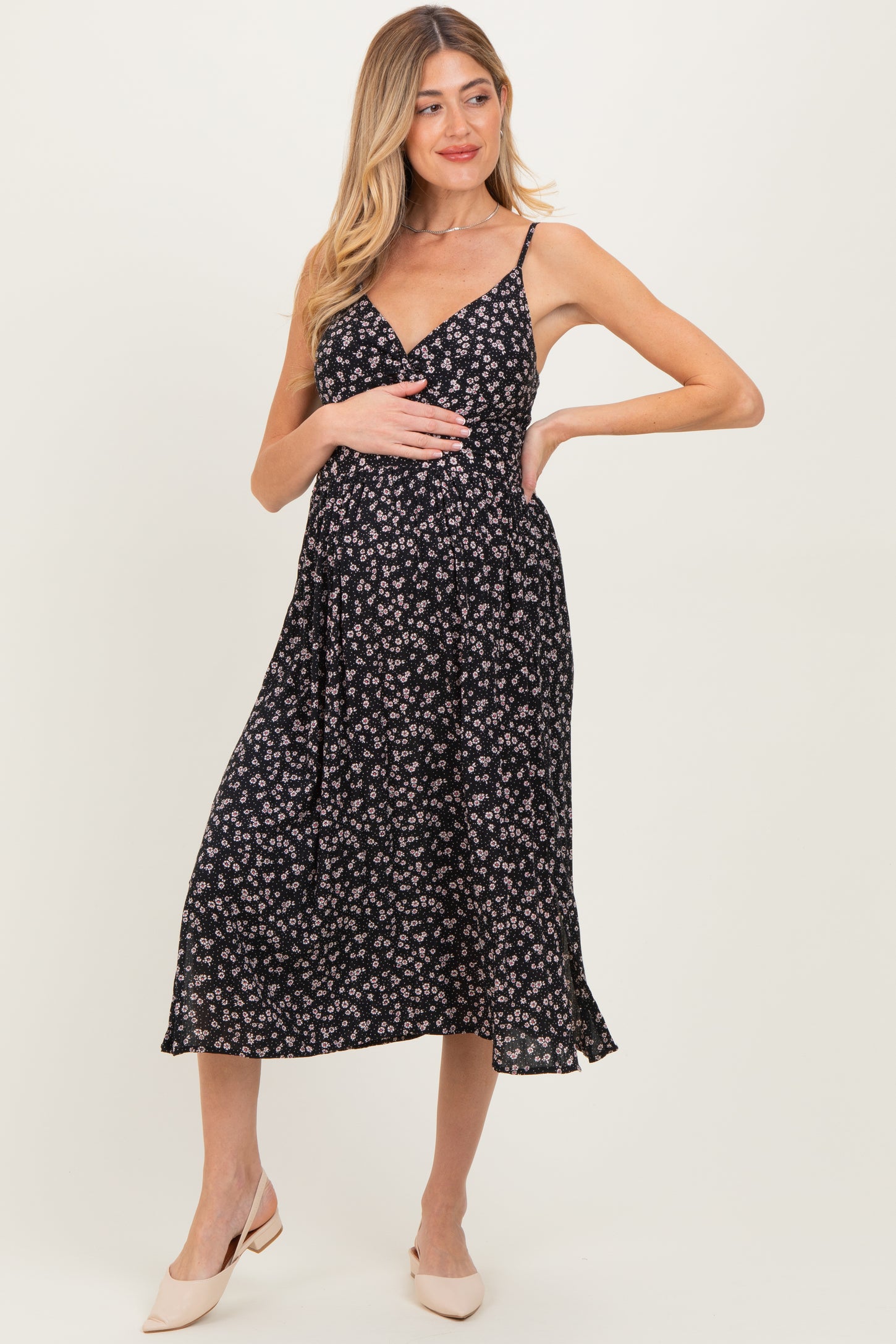 woman wearing a black floral maternity dress with a v-neck and a flowy skirt, showing her baby bump