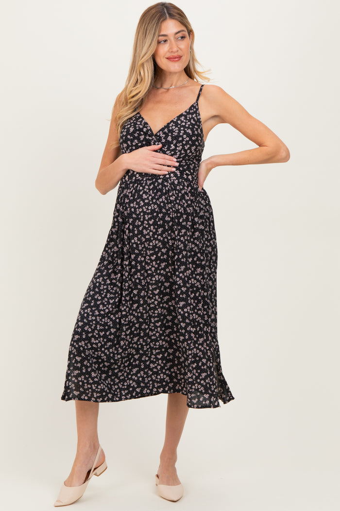 woman wearing a black floral maternity dress with a v-neck and a flowy skirt, showing her baby bump