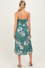 woman wearing a green floral maternity dress with a smocked bodice and flowy skirt, showing off her baby bump from the back
