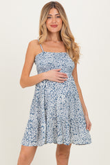 woman wearing a blue floral print maternity dress and holding her baby bump