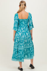woman wearing a turquoise floral maternity maxi dress with a square back and flutter sleeves