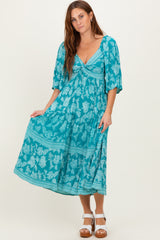 woman wearing a turquoise floral maxi dress with a tied bodice and short puff sleeves