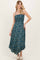 woman wearing a teal floral print maxi dress with spaghetti straps and a smocked bodice, standing elegantly