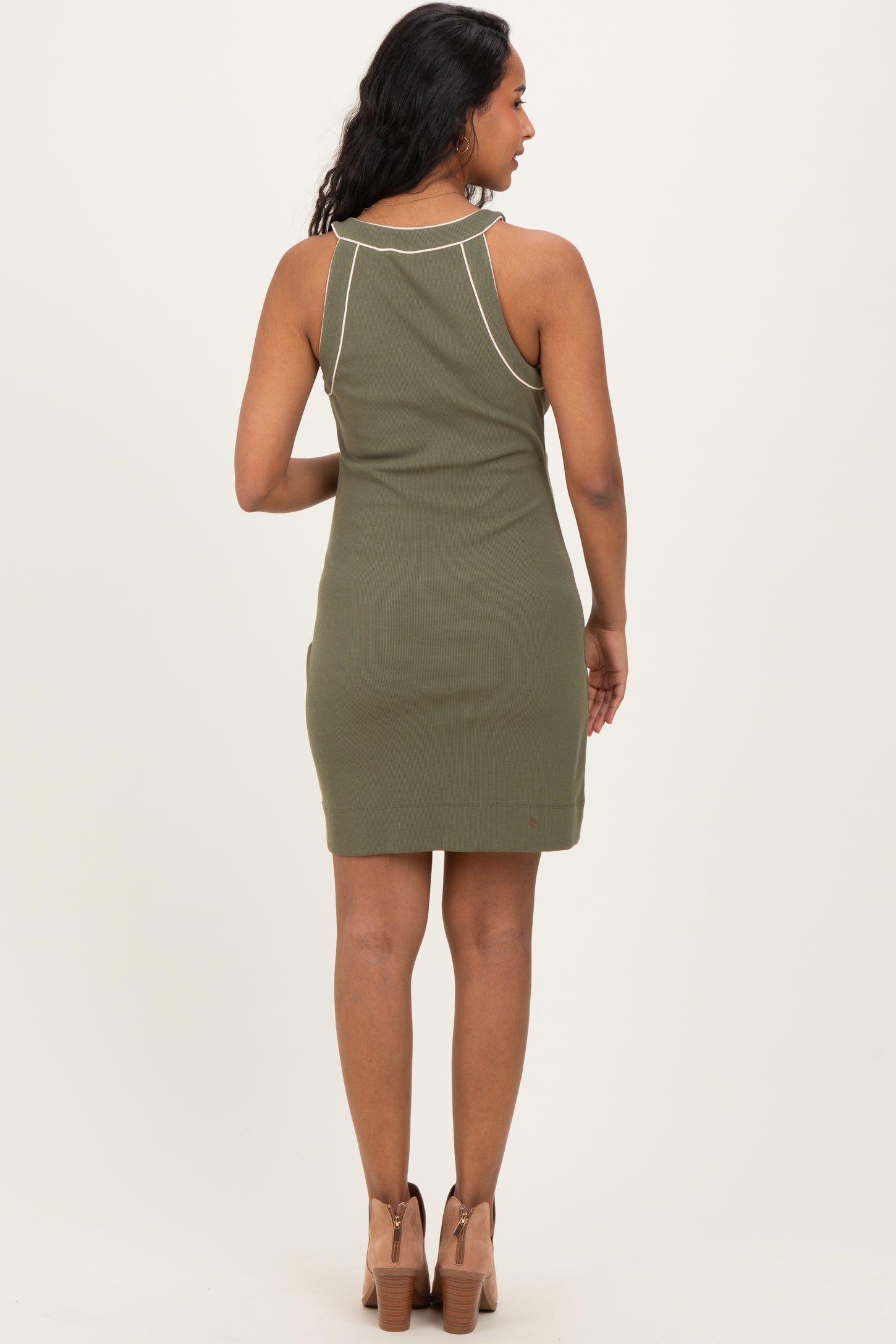 woman wearing a dark green sleeveless maternity dress, viewed from the back, showing a fitted style and knee-length cut