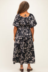 woman wearing a flowy black floral plus-size maxi dress with short puff sleeves and a cinched waist, viewed from the back