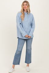 woman wearing a light blue striped button-up shirt and distressed flare jeans with white sneakers