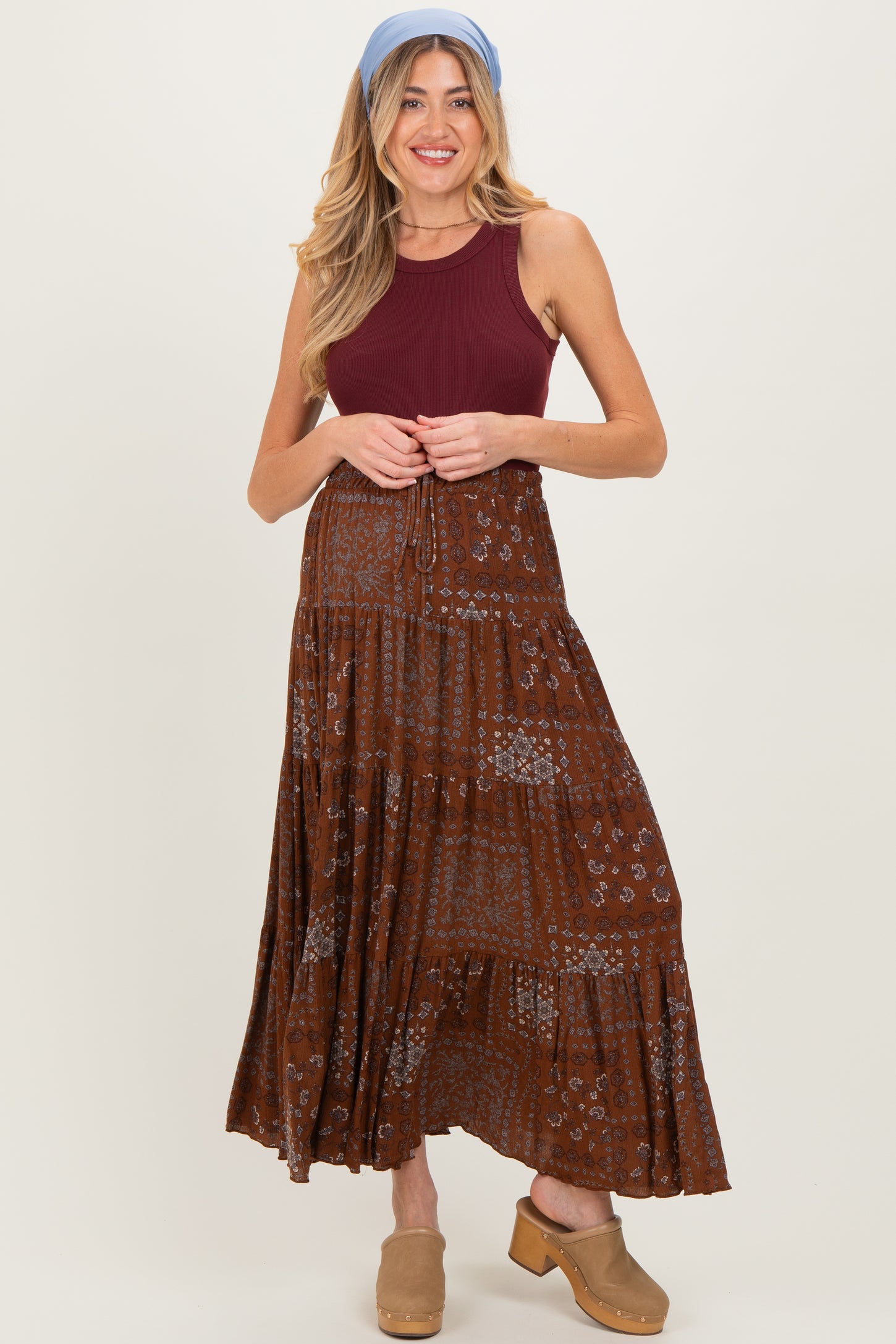 woman wearing a burgundy maternity tank top paired with a brown floral maxi skirt and light blue headband