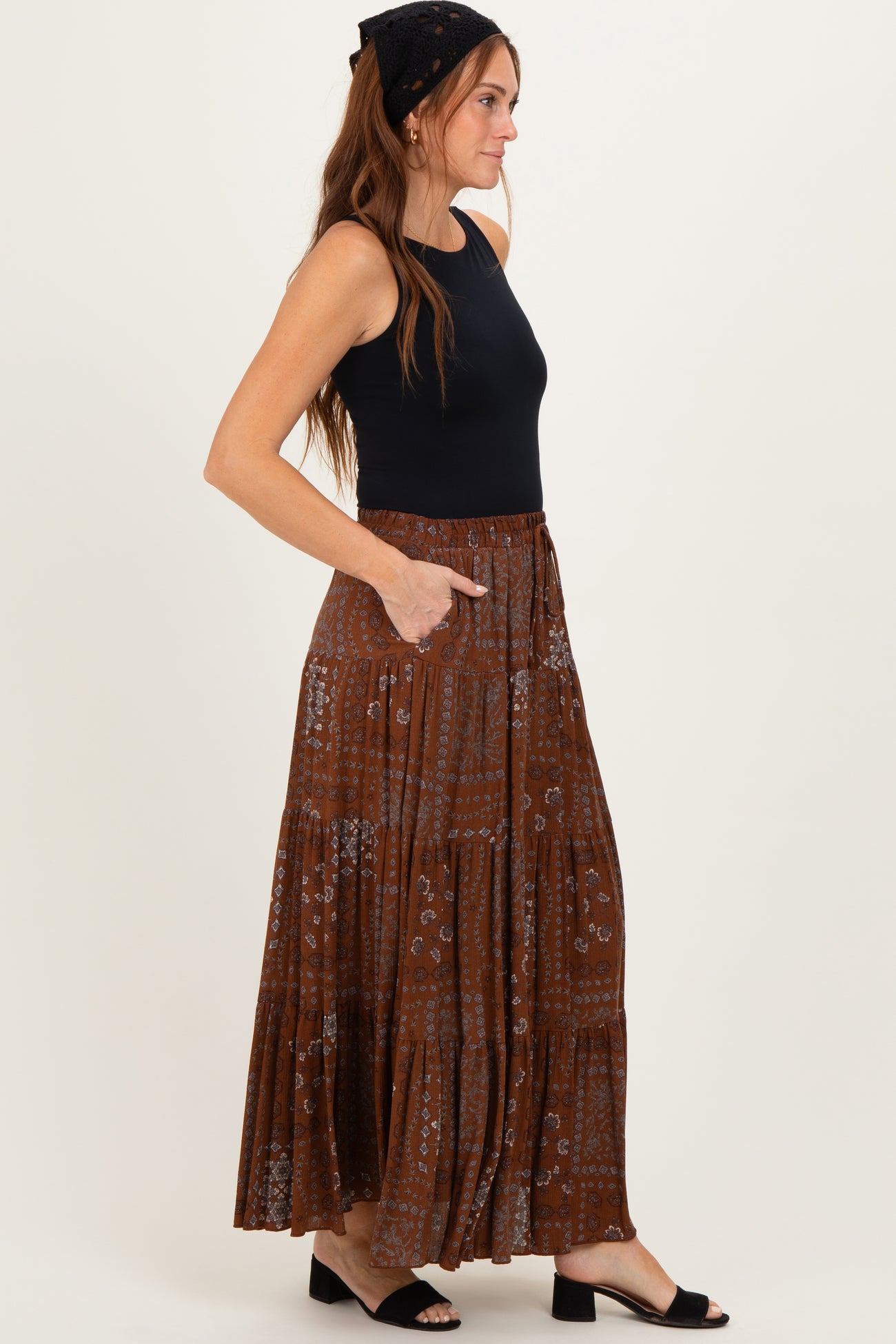 woman wearing a black sleeveless top and a brown patterned maxi skirt with pockets
