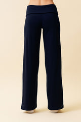 woman wearing navy blue wide-leg yoga pants with a fold-over waistband, viewed from the back