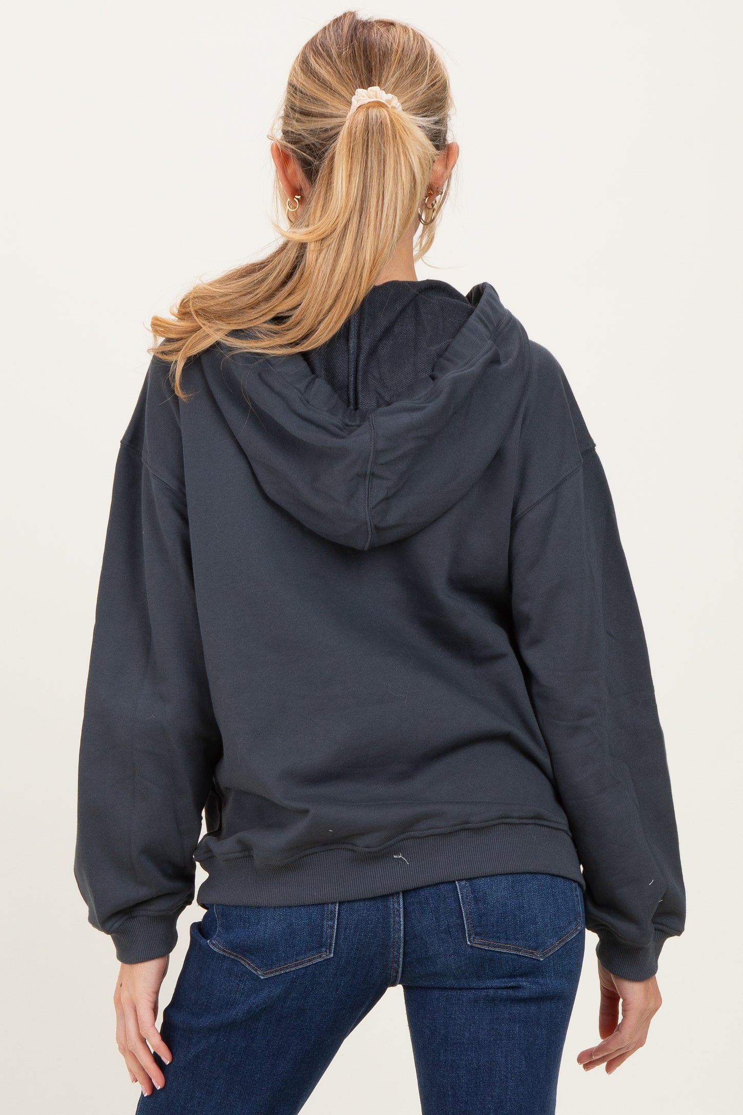 woman wearing a dark gray maternity hoodie with a loose fit, seen from the back with a ponytail hairstyle