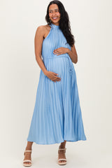 woman wearing a light blue pleated maternity dress with a halter neckline and a baby bump visible