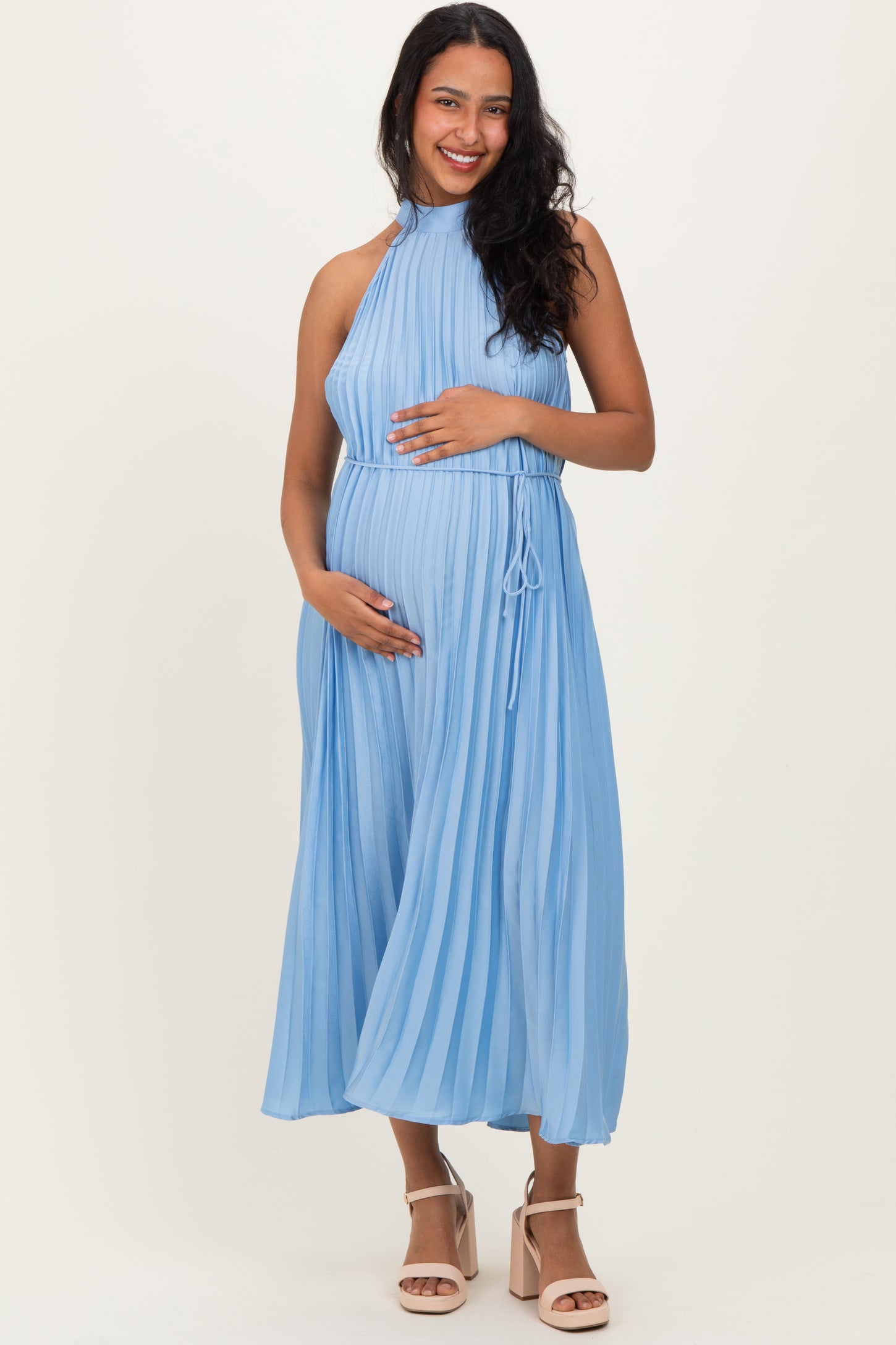 woman wearing a light blue pleated maternity dress and holding her baby bump