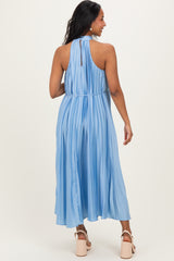 woman wearing a light blue pleated maternity dress with a halter neckline, showing her back
