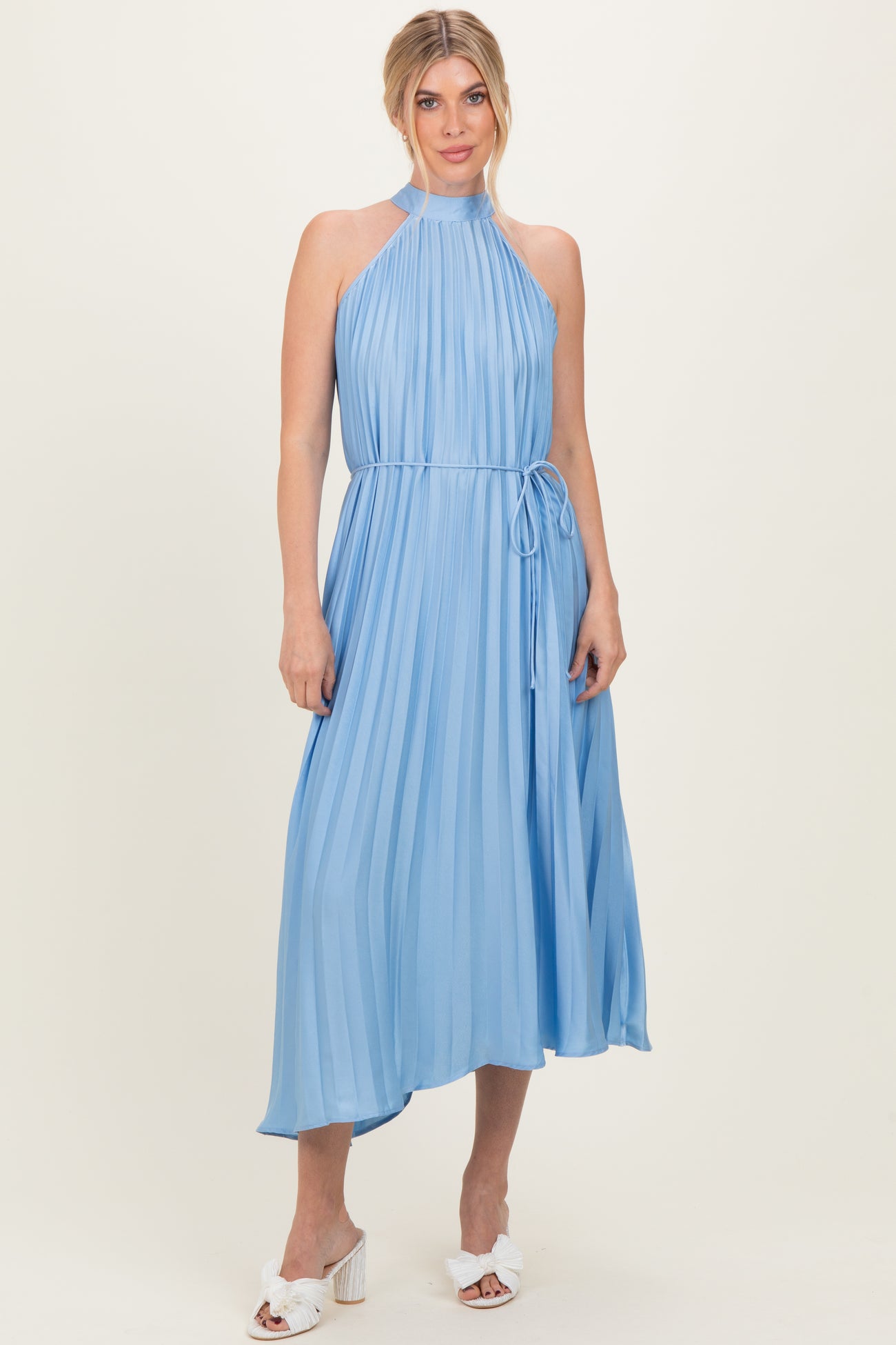 woman wearing a light blue pleated midi dress with a halter neck and a tie waist detail