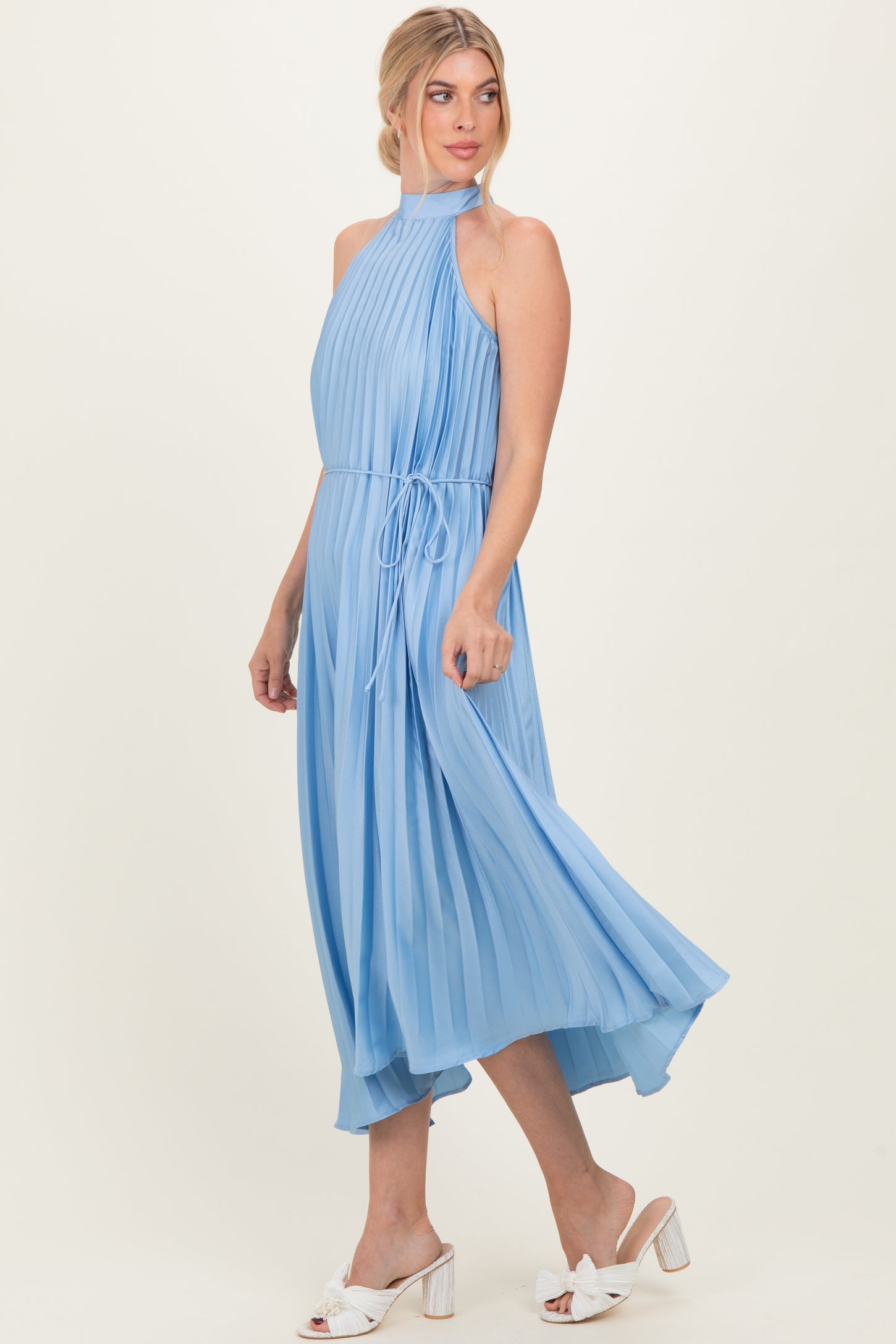 woman wearing a light blue pleated halter dress with a tie waist and flowing skirt