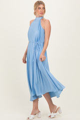 woman wearing a light blue pleated halter dress with a tie waist and flowing skirt