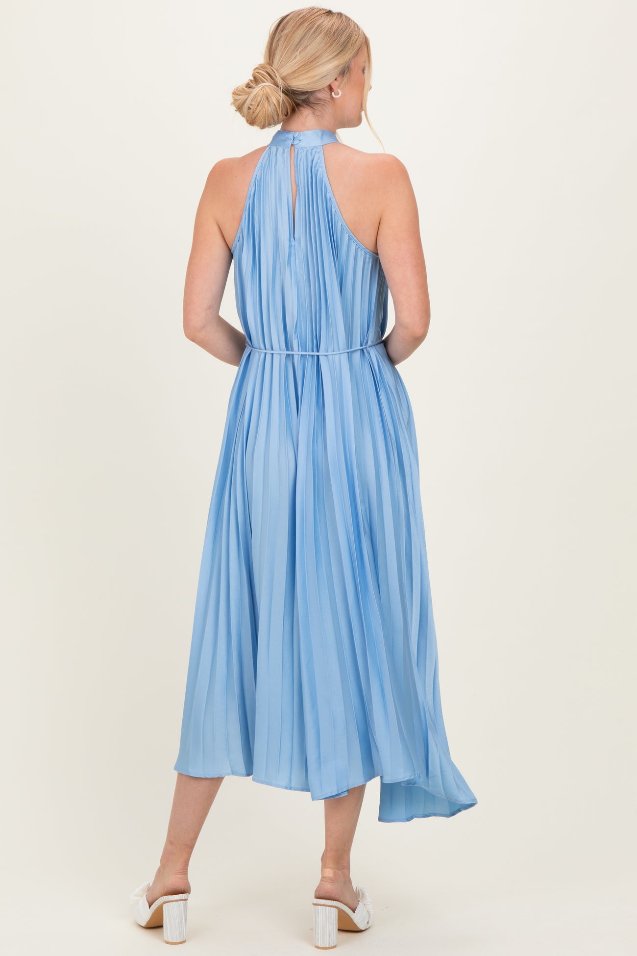 woman wearing a light blue pleated halter neck midi dress with a keyhole back and a flowy skirt