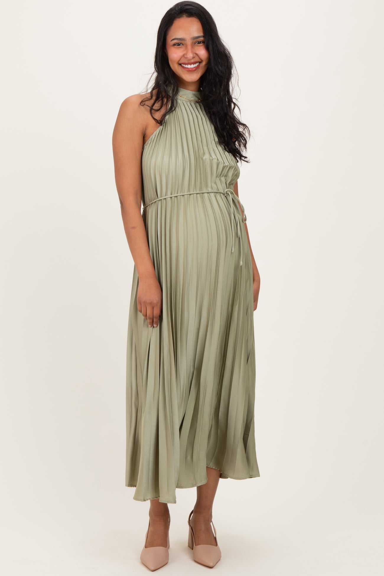 woman wearing a pleated olive green maternity dress with a halter neckline and tied waist, displaying a baby bump