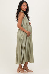 woman wearing a pleated olive green maternity dress and showing her baby bump