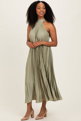 woman wearing a pleated olive green midi dress with a halter neckline and a waist tie, paired with nude heels