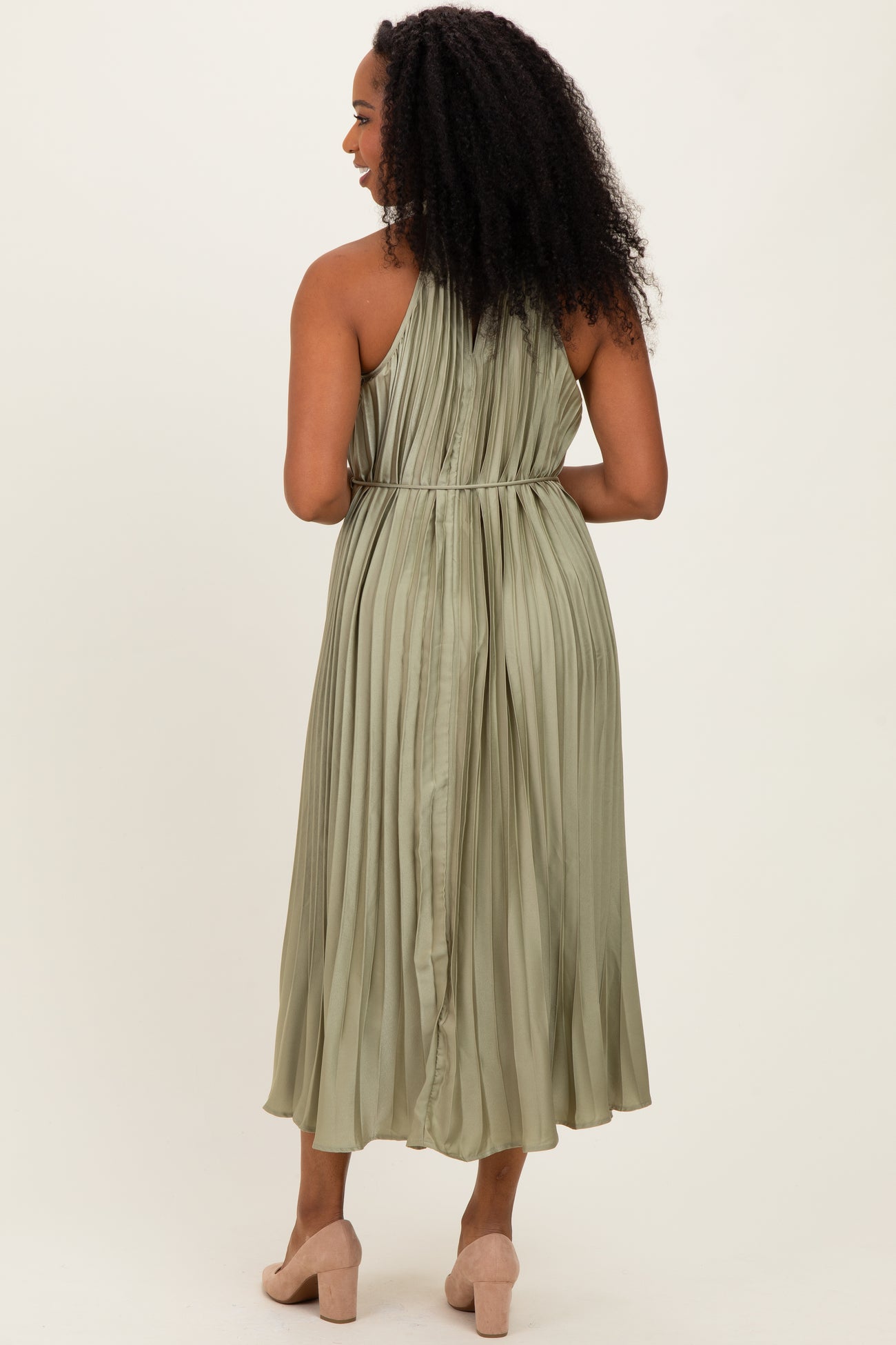 woman wearing a pleated olive green midi dress with a cinched waist, viewed from the back