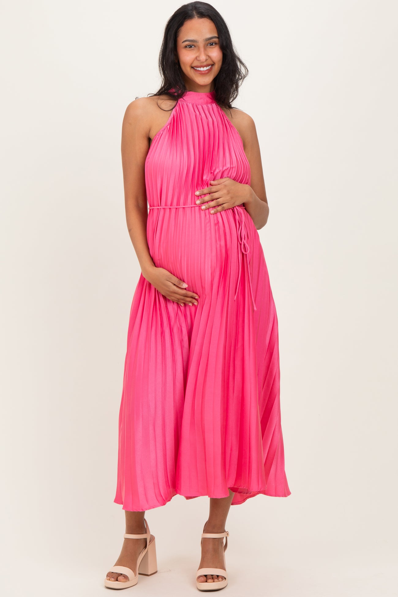 woman wearing a hot pink pleated maternity dress and holding her baby bump