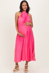 woman wearing a hot pink pleated maternity dress and holding her baby bump