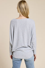 woman wearing a relaxed fit gray long sleeve top with a scoop back and side slits, paired with light blue jeans