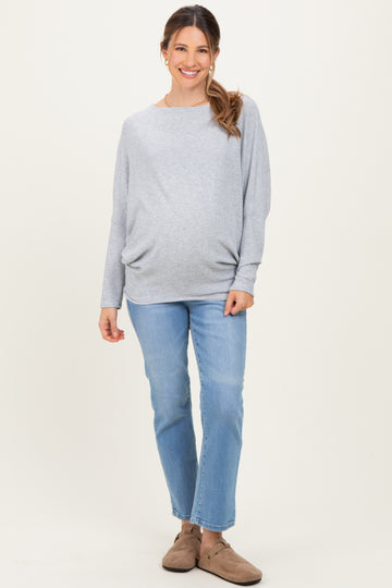 woman wearing a gray maternity sweater and blue jeans, highlighting her baby bump