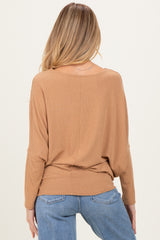 woman wearing a camel long sleeve maternity top with a relaxed fit and back detailing, paired with denim jeans